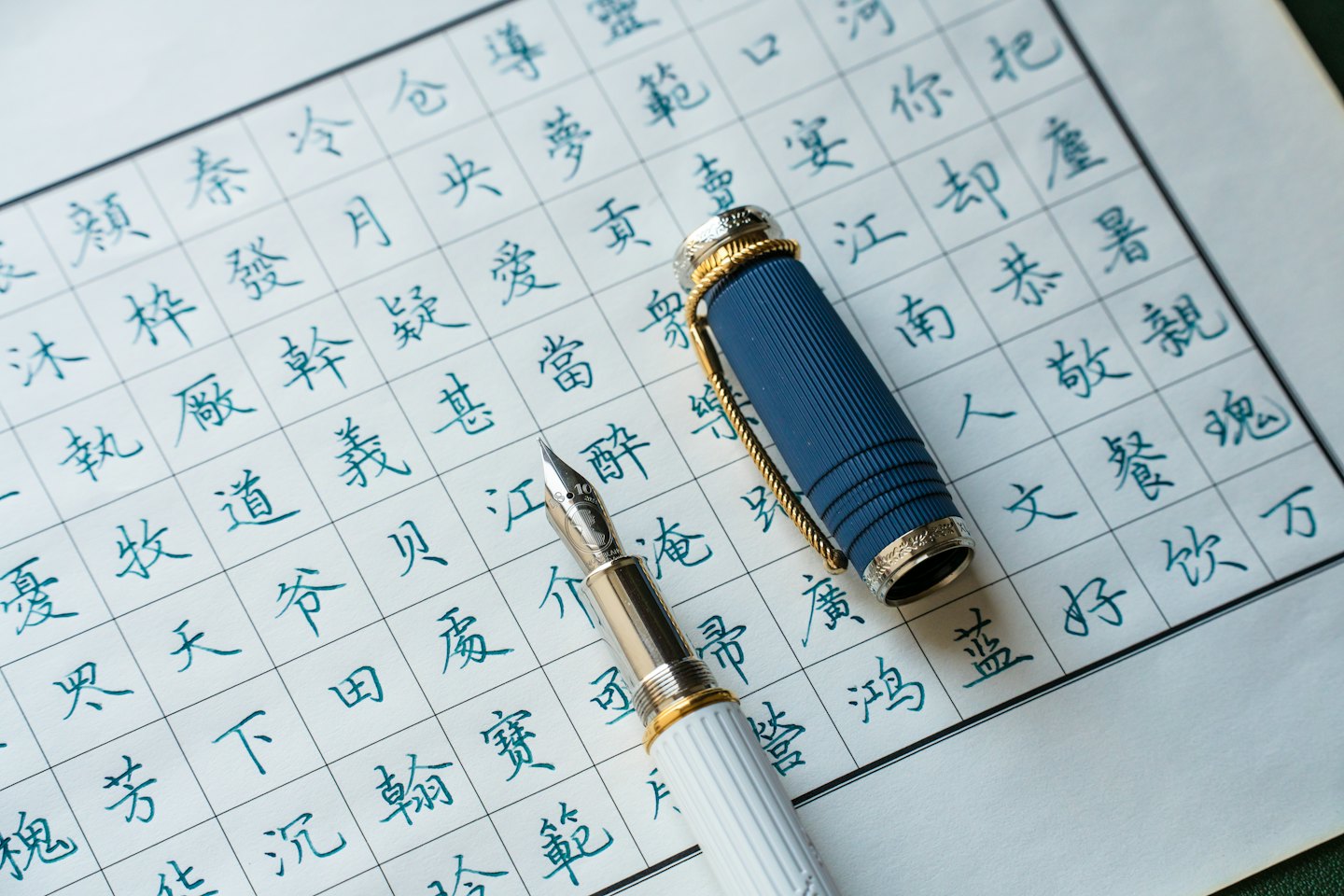 A fountain pen rests on paper covered in Chinese calligraphy.