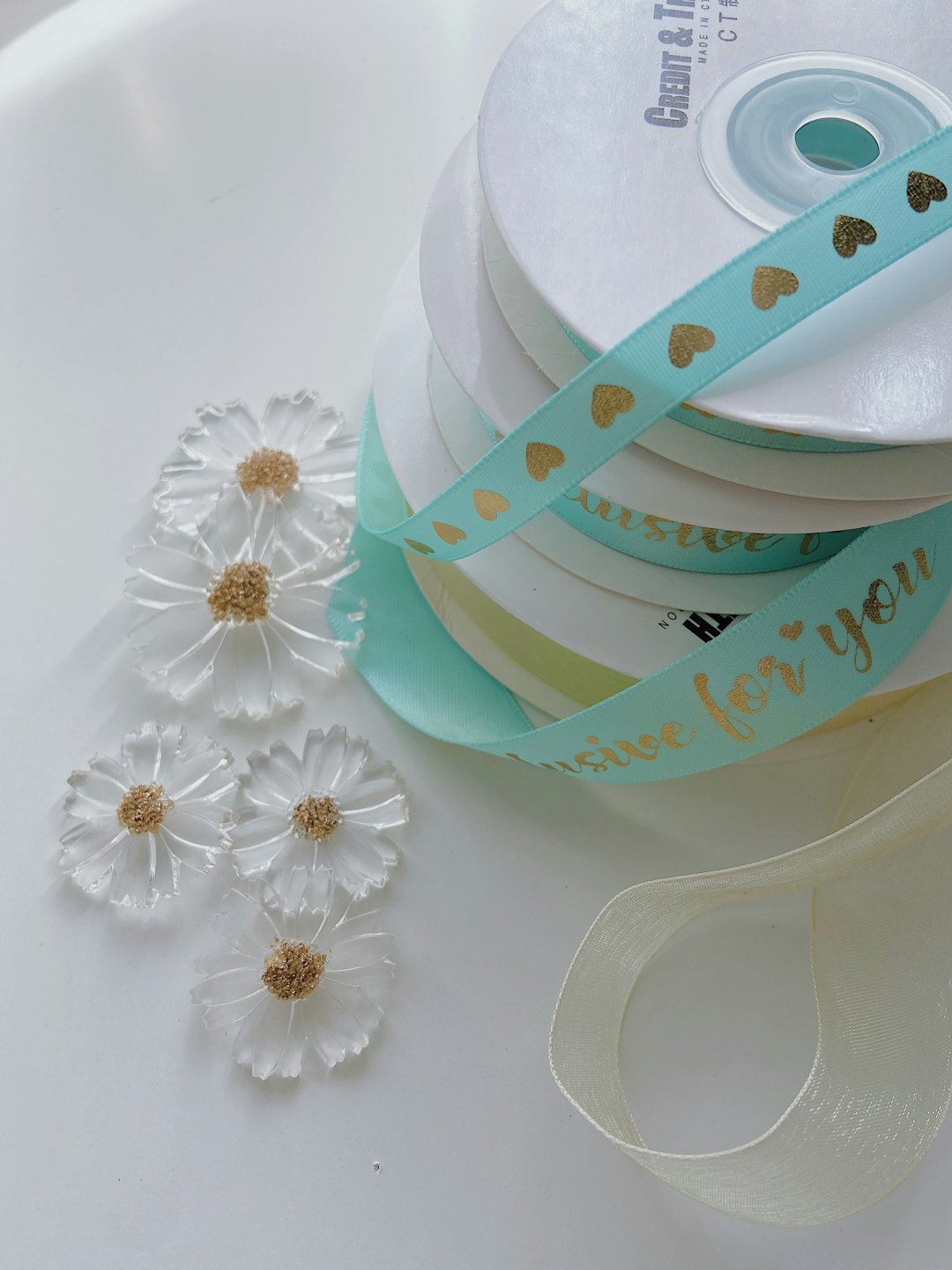 Ribbon spools and daisy decorations arranged for gift wrapping.