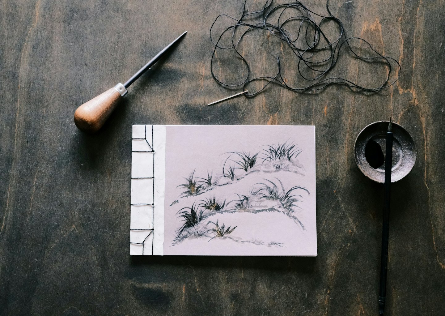 Bookbinding tools and a handcrafted book on wood.