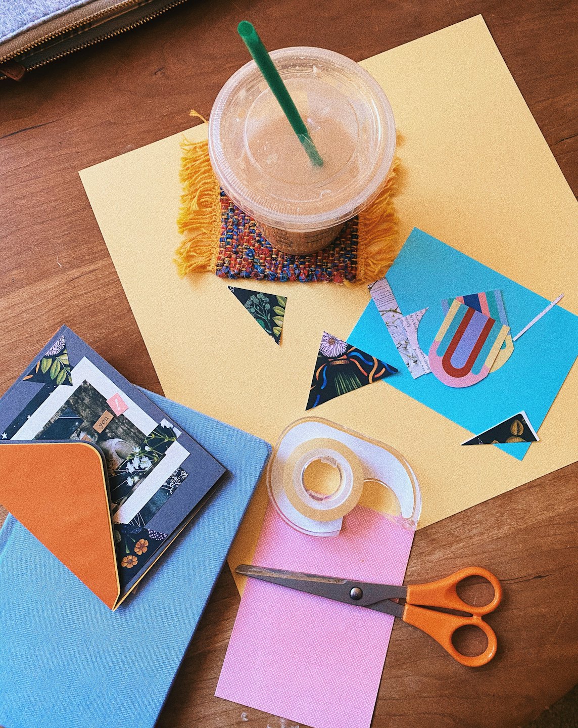 Crafting materials and an iced coffee rest on a table.
